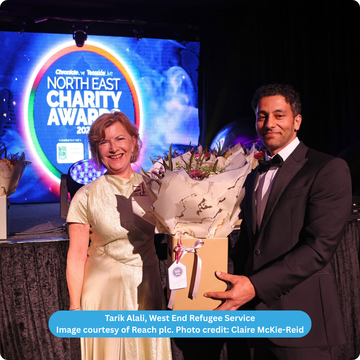 screen in background stating North East Charity Awards 2026. In the foreground a man Tarik and a woman holding a bunch of flowers